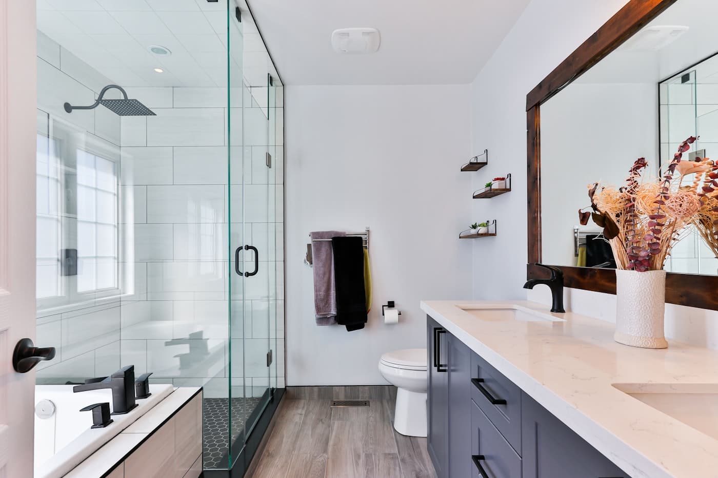 Bright primary bathroom with glass shower and wood-framed mirror